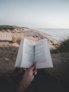 photo of person reading book on beach